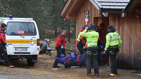 Zwei der Todesopfer werden zu einer H&uuml;tte getragen.