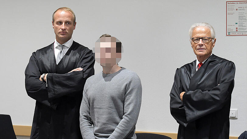 Der Angeklagte neben seinen beiden Verteidigern im Gerichtssaal.