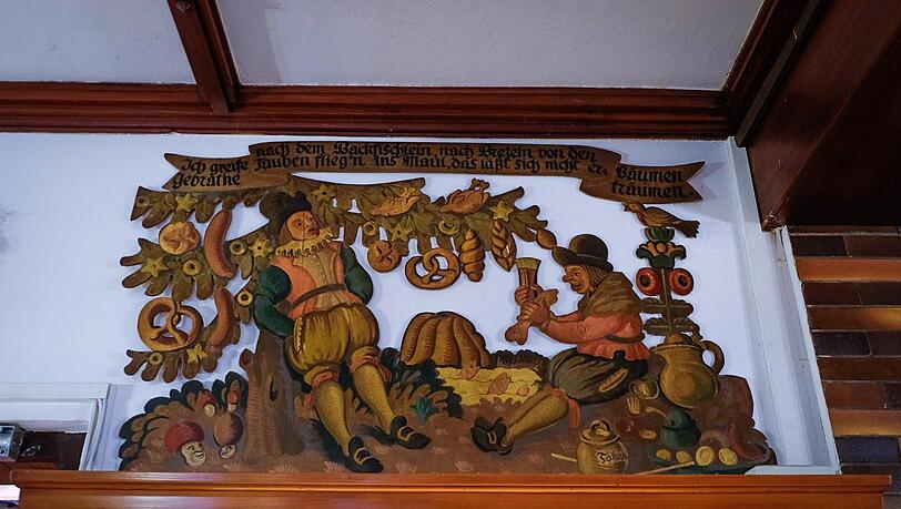 Die urigen Holzfresken des Kunstmalers W. Erlacher zeigen Märchenmotive wie "Das Schlaraffenland" und "Tischlein deck dich".