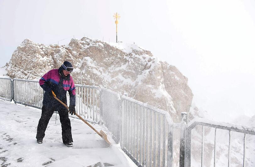Ein Mann räumt Schnee auf der Gipfelterrasse der 2962 Meter hohen Zugspitze bei Grainau.