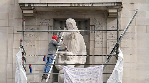 Ein Mann mit einer Spiderman-Maske beschädigt die Statue eines umstrittenen Bildhauers am Hauptquartier der BBC in London.