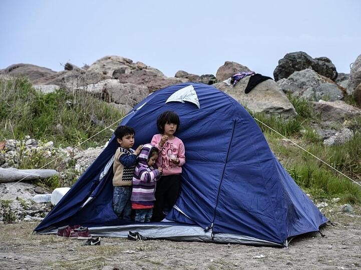 Kinder stehen vor einem Zelt im Dorf Petra auf der Ägäisinsel Lesbos. 53 Kinder und Jugendliche werden nun aus überfüllten Flüchtlingslagern nach Deutschland gebracht.