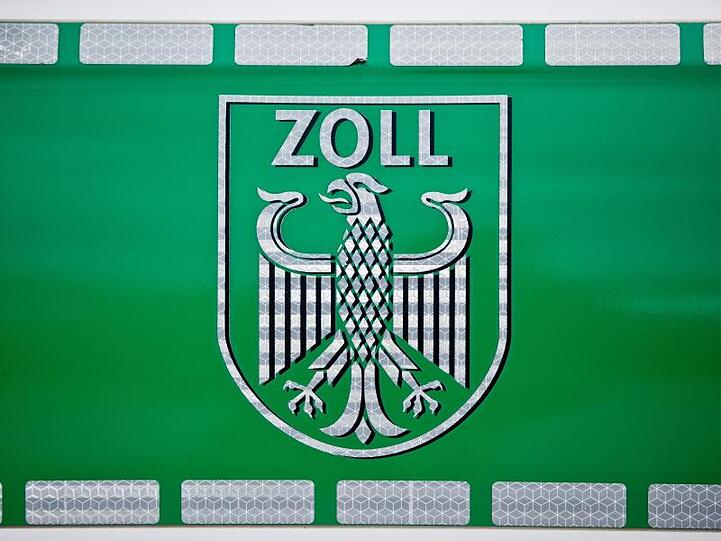 Ein Zollwappen ist auf einem grünem Hintergrund zu sehen. Foto: Daniel Karmann/dpa/Archivbild