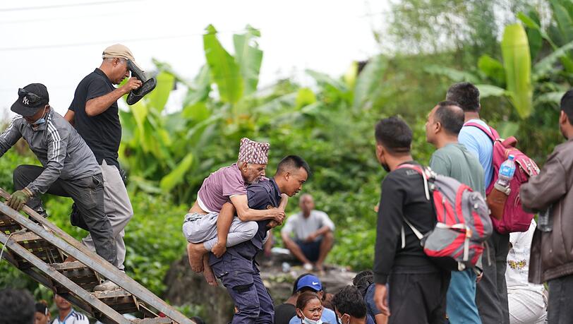 Ein Mann wird im Katastrophengebiet in Nepal von einem Polizisten auf dem Rücken getragen. Ein Mann wird im Katastrophengebiet in Nepal von einem Polizisten auf dem Rücken getragen.
