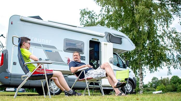 Zwei Camper sitzen vor ihrem Wohnmobil.