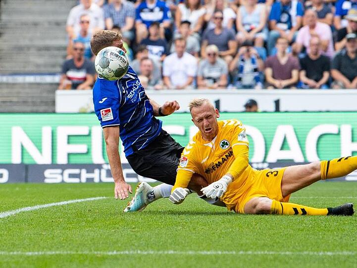Bielefelds Fabian Klos (l) und Sascha Burchert, Torwart von Fürth, kämpfen um den Ball. Foto: Guido Kirchner