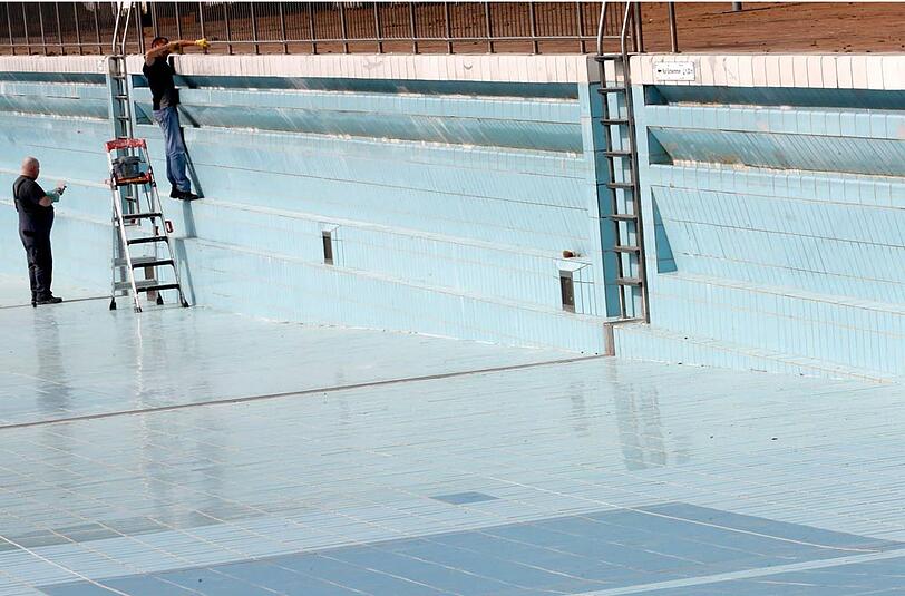 Ein Fliesenleger bessert die Fugen des Wellenbades im Grugapark in Essen aus. Das Freibad wird auf den Saisonstart Anfang Mai vorbereitet.