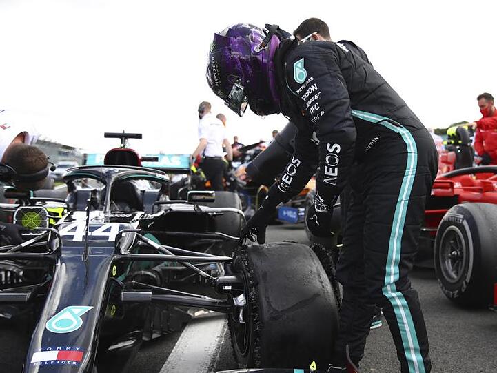 Hamilton schaut sich im Zielbereich den kaputten Reifen an.