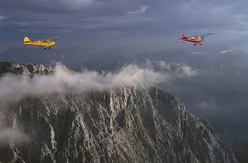 Hier schaut Bodenbender aus seinem Motorflieger auf seine Freunde Tom Werneck (rotes Flugzeug) und Hilde Huber (im gelben) überm Karwendel.