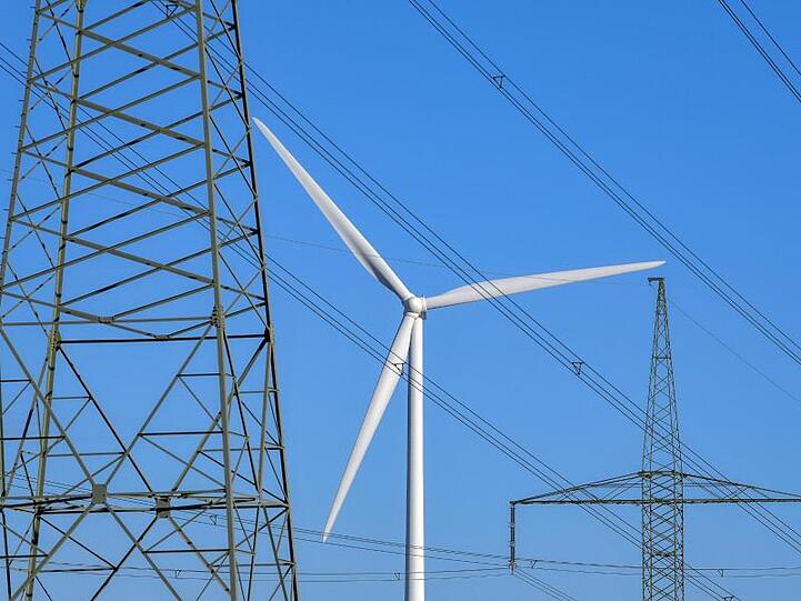 Eine Windenergieanlage ist hinter Hochspannungsleitungen zu sehen. Foto: Patrick Pleul/dpa-Zentralbild/dpa/Archivbild