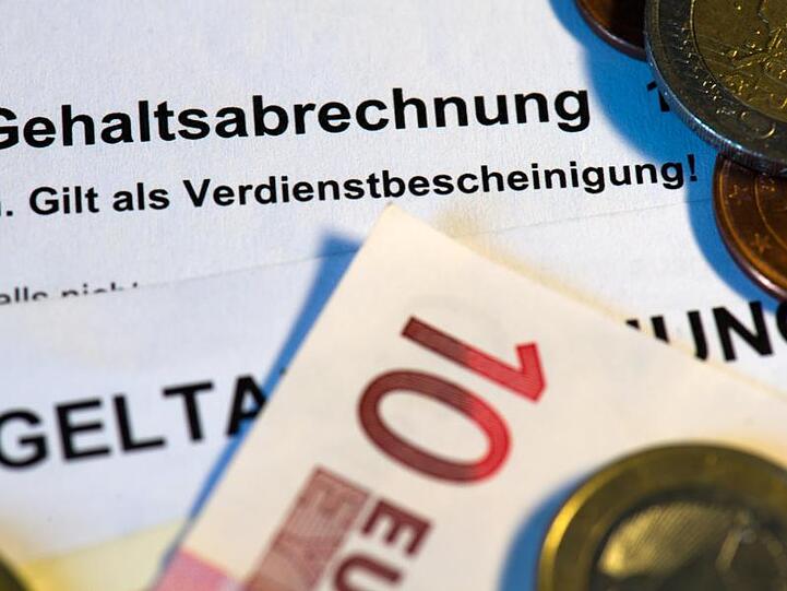 Auf einer Gehaltsabrechnung liegen Euro-Münzen. Foto: Arno Burgi/dpa-Zentralbild/dpa/Illustration