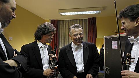 Mariss Jansons verteilt nach dem Konzert Süßigkeiten an die Orchestermitglieder Werner Mittelbach (re.) und Andreas Marschik (re.).