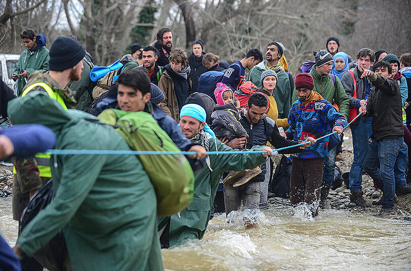 Hunderte Flüchtlinge aus dem Lager in Idomeni durchqueren einen reißenden Fluss auf griechischer Seite, um illegal nach Mazedonien zu gelangen.