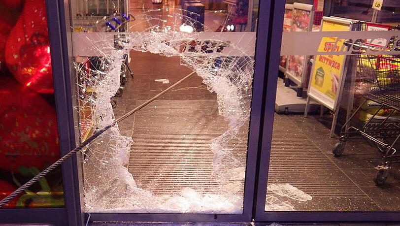 Ein Stahlseil reicht durch die zerbrochene Scheibe in einen Supermarkt in K&ouml;ln. Am Ende wurde ein Geldautomat angebunden. Mit Seil und Lkw hatten Unbekannte vergeblich versucht, den Automaten aus der Wand zu rei&szlig;en.