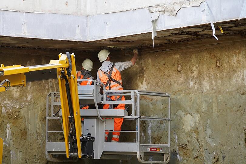 Reges Treiben auf der Baustelle am Marienhof: Bauarbeiter inspizieren die Betondecke, welche die Baugrube nach oben abschließt.