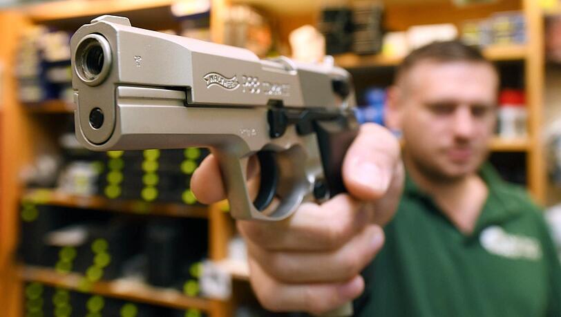 Ein Verkäufer in einem Waffengeschäft zeigt eine Schreckschusspistole vom Typ Walther P 88 Compact Kaliber 9 mm PAK. Vom scharfen Original ist sie optisch kaum zu unterscheiden.