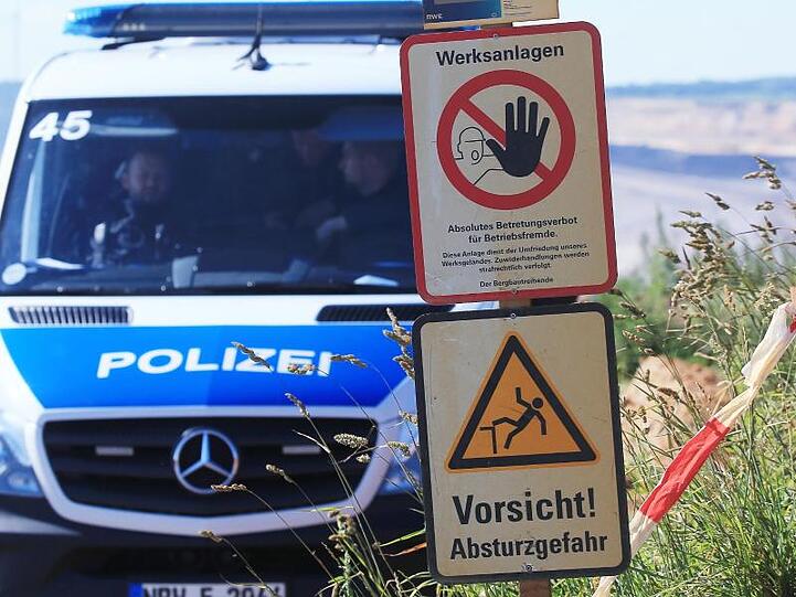 Polizeifahrzeug am Tagebau Garzweiler neben Warnschildern mit den Aufschriften "Werksanlagen".