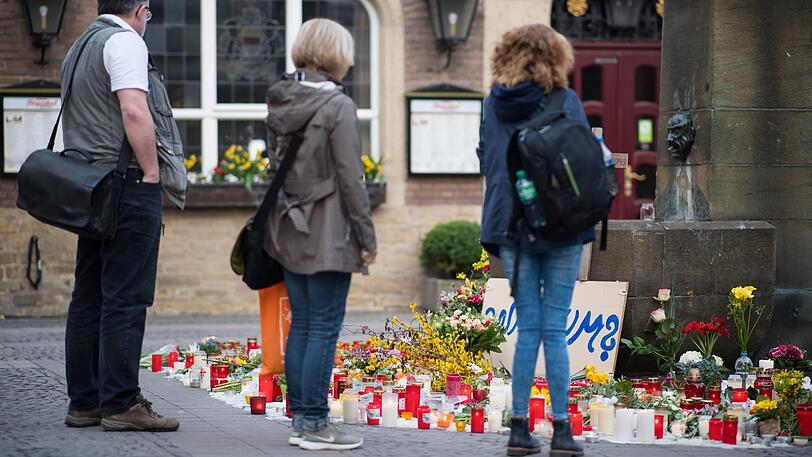 Passanten stehen vor den niedergelegten Kerzen und Blumen am Tatort vor dem Kiepenkerl. Ein Mann war am 07.04. mit einem Kleintransporter vor dem Restaurant in eine Gruppe von Menschen gerast und hatte zwei von ihnen getötet. Anschließend erschoss er sich nach Polizeiangaben in dem Wagen selbst.