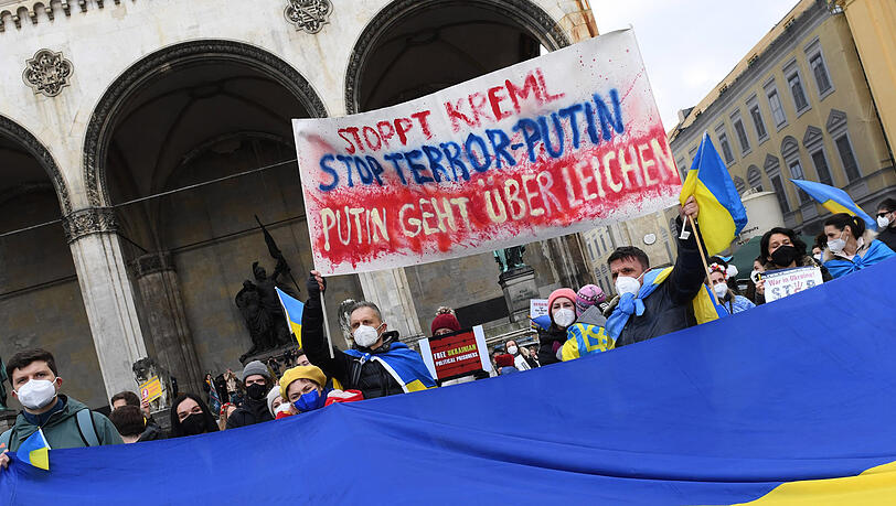 Demonstranten mit einem Plakat "Stoppt Kreml, Stoppt Terror Putin, Putin geht über Leichen" am Odeonsplatz.