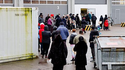 Menschen stehen bei einer Essenausgabe in der Landesunterkunft der Gemeinde Seeth im Kreis Nordfriesland Schlange.