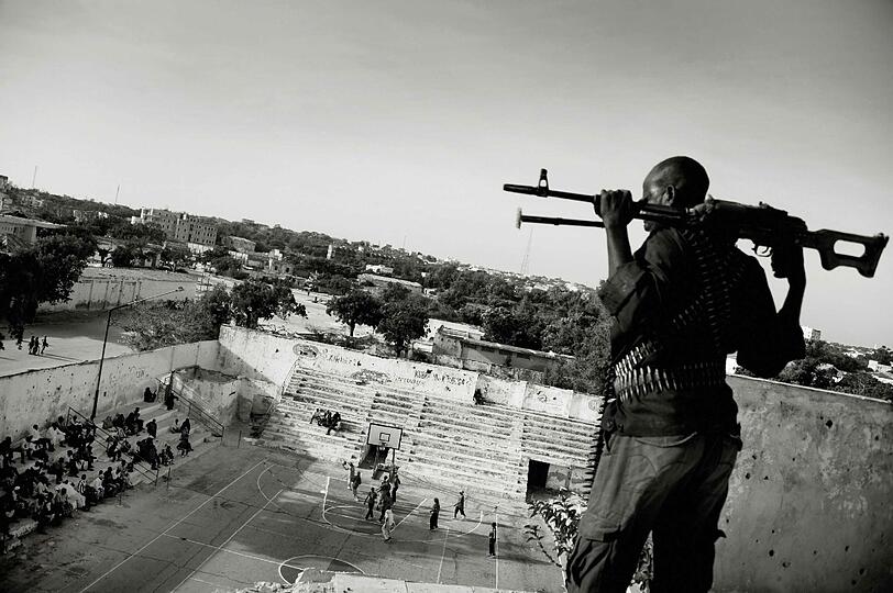 Ein bewaffneter Mann beobachtet ein Basketballspiel in Somalia.