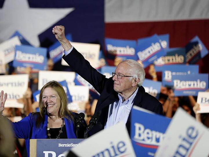 Bernie Sanders und seine Frau Jane stehen bei einer Wahlkampfveranstaltung inmitten von Anhängern.