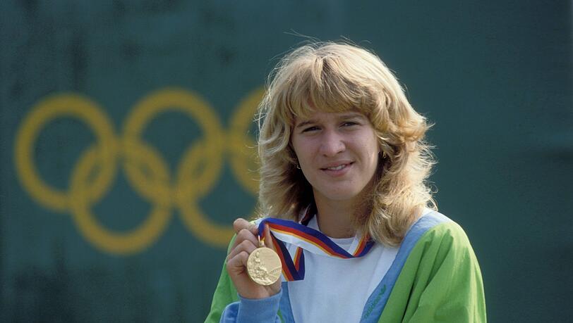 Da is’ das Ding: Nach dem Finalsieg gegen Gabriela Sabatini (u.) gab’s für Steffi Graf Olympia-Gold, bei den Grand Slams dagegen Pokale. Da is’ das Ding: Nach dem Finalsieg gegen Gabriela Sabatini (u.) gab’s für Steffi Graf Olympia-Gold, bei den Grand Slams dagegen Pokale.