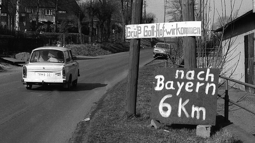 Mit dem Trabi geht's von Thüringen aus ins benachbarte bayerische Hof. Die Schilder am Straßenrand, wie hier in Hirschberg, zeigen die Aufbruchstimmung.