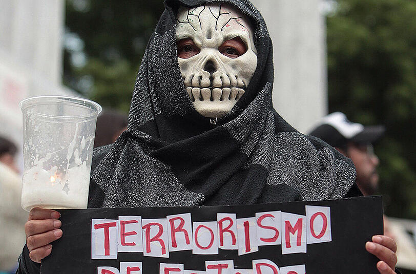 Eine Demonstrantin trägt bei einem Protestzug für Ermittlungen zum Mord an Rubén Espinosa ein Schild mit der Aufschrift "Staatsterrorismus". Kritiker unterstellen dem Gouverneur von Veracruz, Javier Duarte, eine Verstrickung in den Fall.