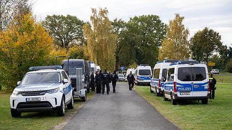 Polizeiautos stehen auf einer Wiese in Tauche.