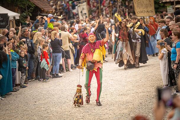 Maxx, der Narr, führt seine Königsmarionette übers Gelände beim Umzug vor dem Ritterturnier. Maxx, der Narr, führt seine Königsmarionette übers Gelände beim Umzug vor dem Ritterturnier.