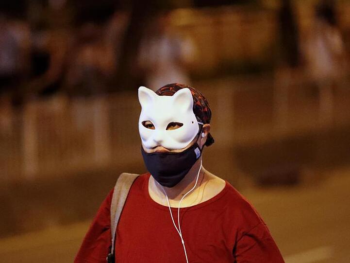 Ein maskierter Demonstrant läuft über eine Straße. Demonstranten wehren sich gegen das Notstandsgesetz der Regierung.