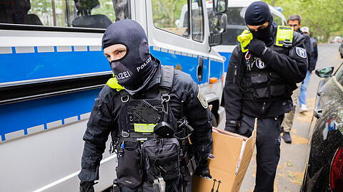 Polizisten tragen bei einer Hausdurchsuchung in Berlin-Kreuzberg einen Karton zu einem Fahrzeug. Dem zugrunde liegen Ermittlungen aus München.