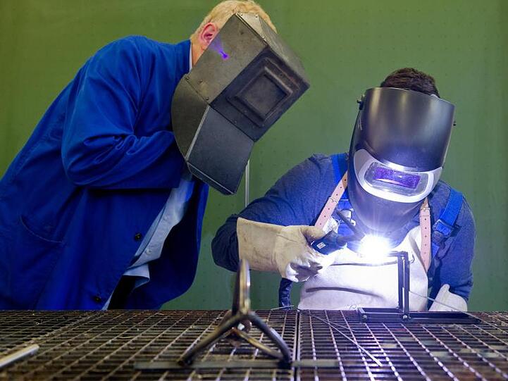 Ein Auszubildender (r) setzt eine Schweißnaht an ein Metallteil.