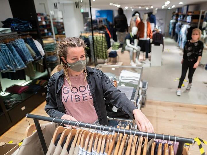 Eine junge Frau trägt in einem Bekleidungsgeschäft in Hamburg einen Mund- und Nasenschutz. Der von den Grünen vorgeschlagene Gutschein soll im stationären Handel, für stationäre Dienstleistungen oder in der Gastronomie eingelöst werden können.