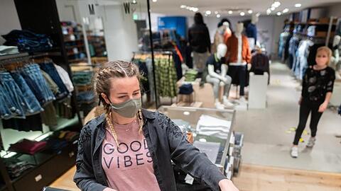 Eine junge Frau trägt in einem Bekleidungsgeschäft in Hamburg einen Mund- und Nasenschutz. Der von den Grünen vorgeschlagene Gutschein soll im stationären Handel, für stationäre Dienstleistungen oder in der Gastronomie eingelöst werden können.