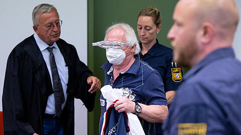 Der Angeklagte (mit Alubrille) im Prozess um gefälschte Impfpässe steht vor Beginn der Verhandlung zusammen mit seinem Anwalt Franz Wittl (l.) im Gerichtssaal.