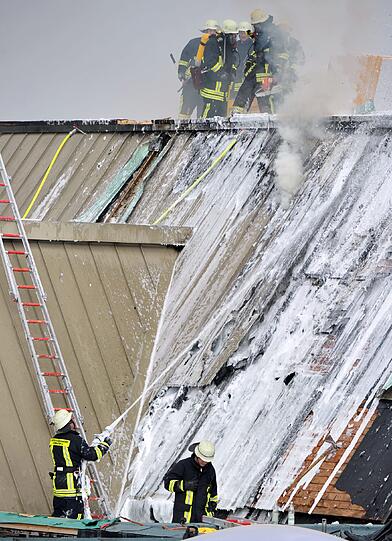 Feuerwehrmänner bekämpfen am Dienstag in Augsburg einen Brand am Dach der Universität. Nach Schweißarbeiten kam es auf der Baustelle der Mensa, die gerade saniert wird, zu einem Brand. An der Uni sind gerade Semesterferien, es gab keine Verletzten.