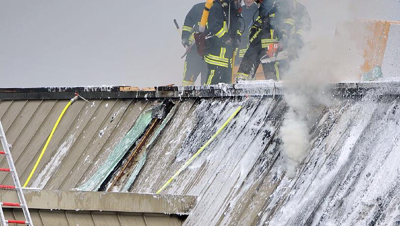 Feuerwehrmänner bekämpfen am Dienstag in Augsburg einen Brand am Dach der Universität. Nach Schweißarbeiten kam es auf der Baustelle der Mensa, die gerade saniert wird, zu einem Brand. An der Uni sind gerade Semesterferien, es gab keine Verletzten.