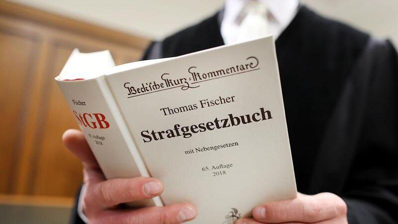 Eine Person mit juristischer Funktion hält ein Strafgesetzbuch in den Händen. Foto: Oliver Berg/dpa/Archivbild