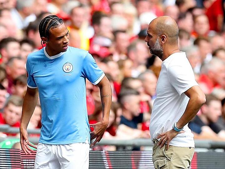 Manchester Citys Leroy Sané (l) spricht nach seiner Auswechslung mit Trainer Pep Guardiola.