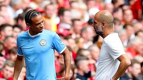 Manchester Citys Leroy Sané (l) spricht nach seiner Auswechslung mit Trainer Pep Guardiola.