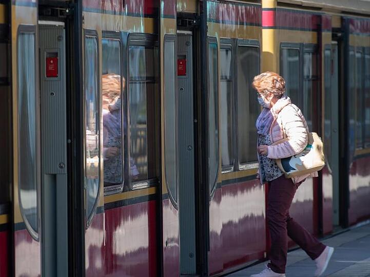 Eine Frau mit Mundschutz steigt in eine Berliner S-Bahn ein.