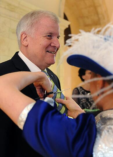 Eine Gardetänzerin schneidet bei einem Empfang für Faschingsgesellschaften in der Staatskanzlei in München dem Horst Seehofer die Krawatte ab.