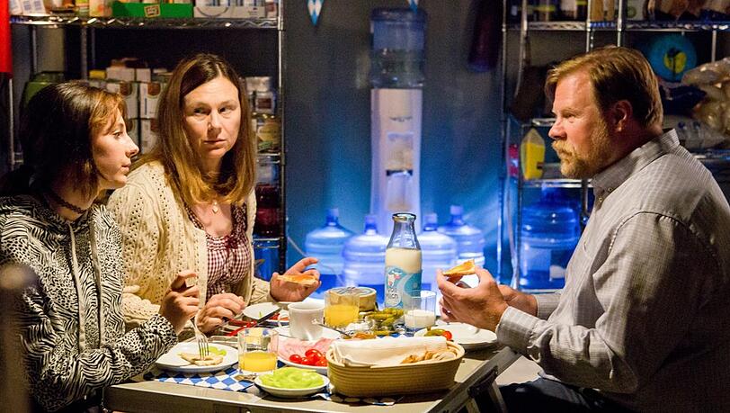 "Alles finster": Marie (Laila Marie Noëlle Padotzke), ihre Mutter Carola (Bettina Mittendorfer) und Jens (Michael A. Grimm) unterhalten sich im Prepper-Keller beim Essen.