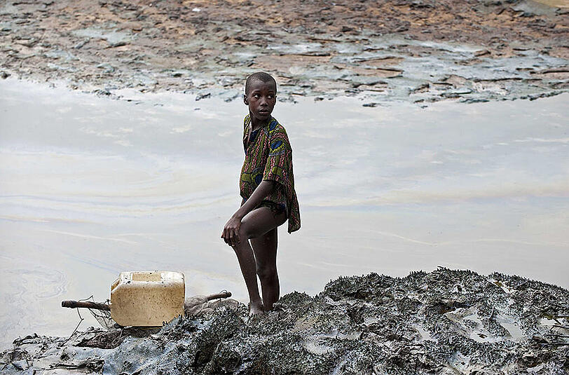 Ein Junge steht auf am ölverschmierten Ufer einer Bucht im Nigerdelta. Shell zahlt im Streit um ausgelaufenes Öl insgesamt 55 Millionen Pfund Fischer und Farmer.