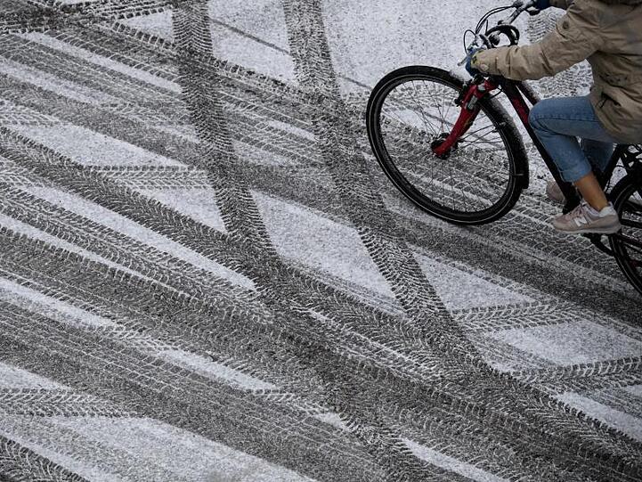 Eine Frau fährt mit ihrem Fahrrad über eine schneebedeckte Straße. Foto: Sven Hoppe/dpa/Symbolbild