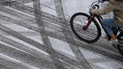 Eine Frau fährt mit ihrem Fahrrad über eine schneebedeckte Straße. Foto: Sven Hoppe/dpa/Symbolbild