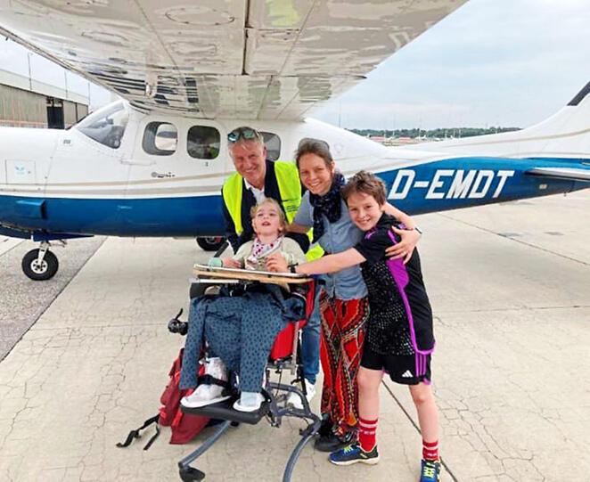 "Flying Hope"-Pilot Georg Kraus mit einer Familie vor dem Flugzeug.