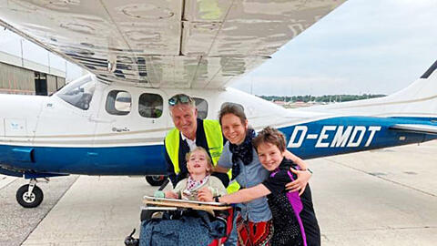 "Flying Hope"-Pilot Georg Kraus mit einer Familie vor dem Flugzeug.